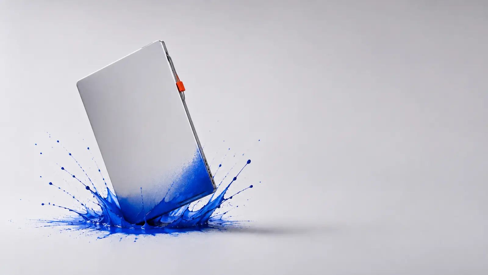 Un ordinateur portable argenté frappe une surface d’encre cobalt.
